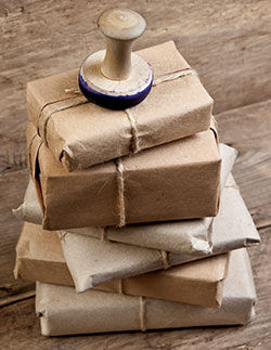 Six parcels wrapped in brown paper and twine with a stamp on top