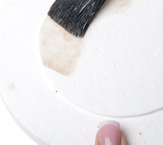 a paintbrush brushing liquid onto a plate