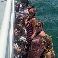 Group of people on a boat, smiling at the camera