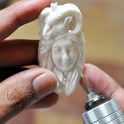Bone carving of a ram and a human face